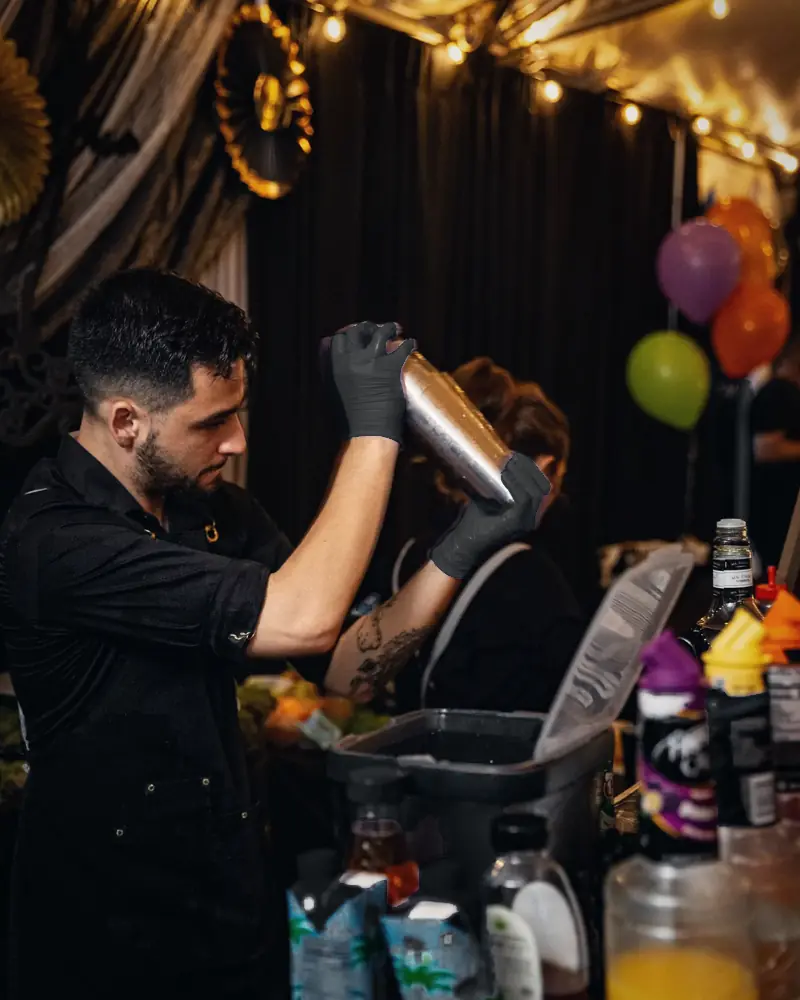 Bartender shaking a cocktail behind a decorated party bar