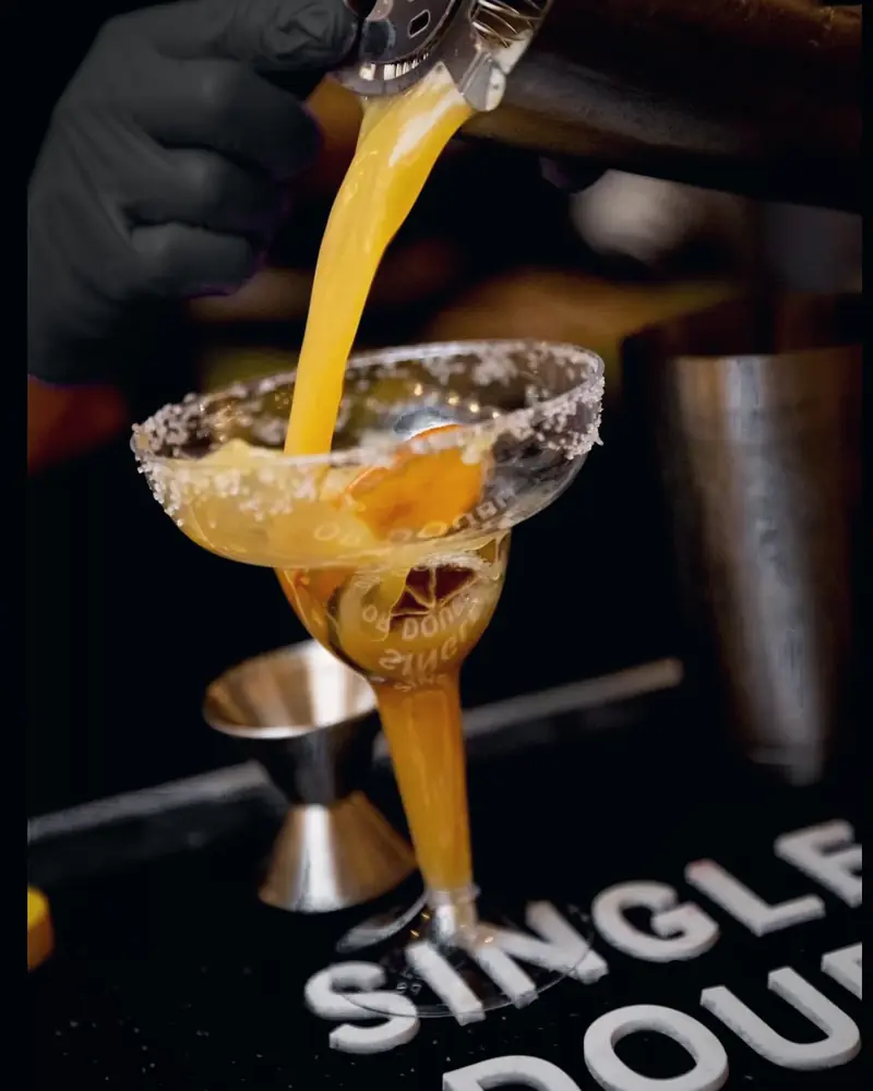 A margarita being strained into a salt-rimmed glass